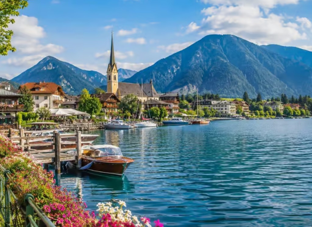 A lakeside walking path beside Lake Tegernsee with hills in the background.