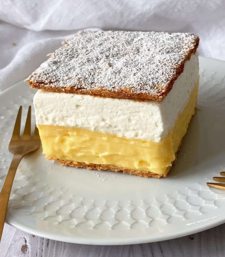 A slice of Bled cream cake with puff pastry, vanilla cream and whipped cream.