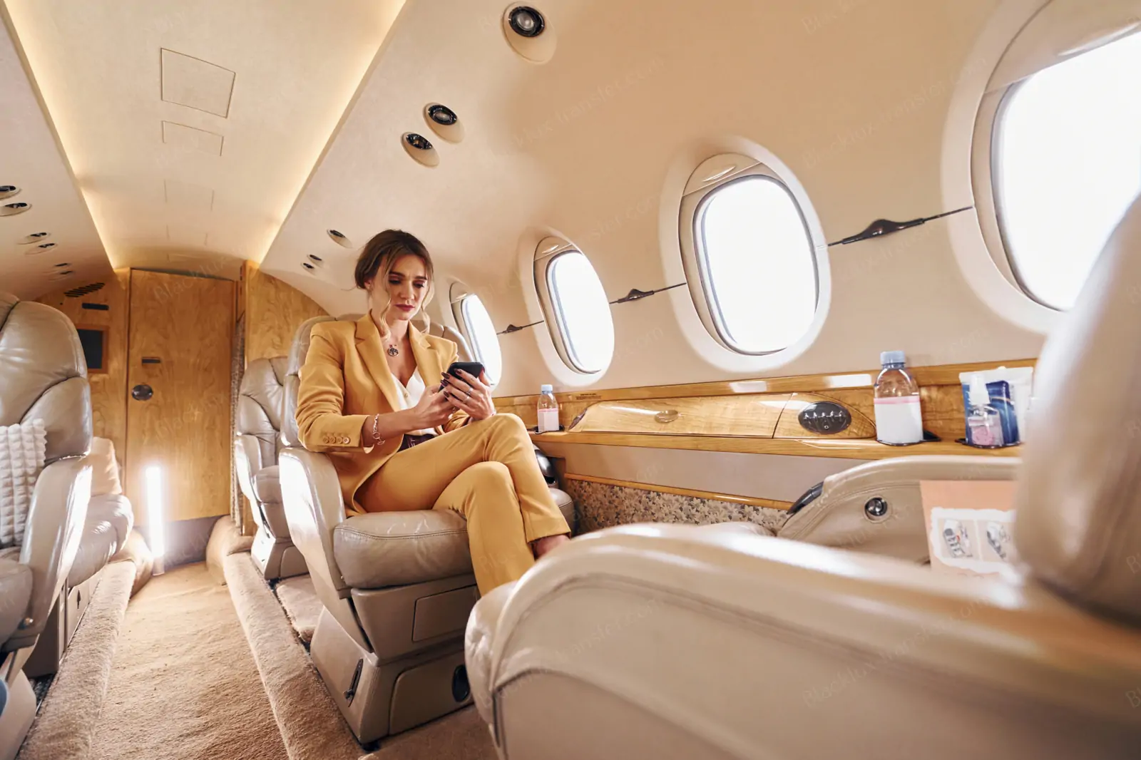 Passenger seated beside a table in a private jet cabin
